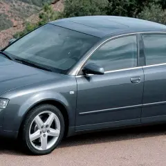 Szary sedan Audi A4 B6, produkowany w latach 2000-2006, parkuje na tle górskiego krajobrazu.