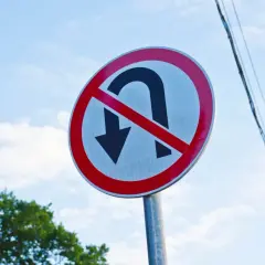 Znak zakazu zawracania na skrzyżowaniu. Nie można tu zawracać, trzeba jechać prosto lub skręcić.