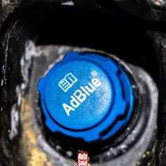 Niebieski korek wlewu AdBlue w samochodzie, z widocznym logo i napisem.