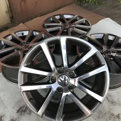 Cztery aluminiowe felgi Volkswagen z logo, ułożone na ziemi.