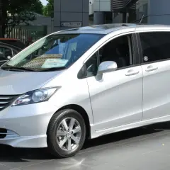 Srebrny Honda Freed stoi na tle budynku.
