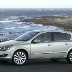 Srebrny Opel Astra H, popularny model z lat produkcji 2004-2009, zaparkowany na tle skalistego wybrzeża i wzburzonego morza.