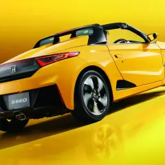 Żółta Honda S660 z otwartym dachem, widziana z tyłu, błyszczy na tle.