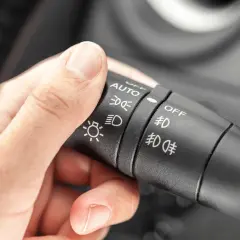 Dłoń reguluje przełącznik świateł: auto, światła mijania, światła dzienne, wyłączone.