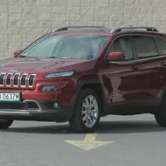 Czerwony Jeep Cherokee KL z polskimi tablicami rejestracyjnymi stoi na parkingu.