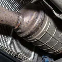 Podwozie auta z wyciętym DPF. Widoczny skorodowany katalizator i osłona termiczna.
