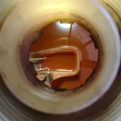 Pomarańczowy kolor płynu chłodniczego w zbiorniczku, widoczny wewnątrz plastikowego otworu.