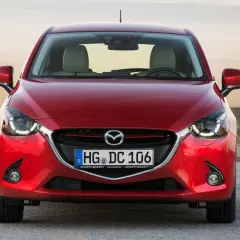 Czerwona Mazda 2 DY z przodu, z widocznymi światłami LED i tablicą rejestracyjną.