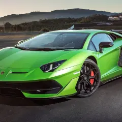 Jaskrawozielony Lamborghini Aventador SVJ na torze wyścigowym, z górami w tle.