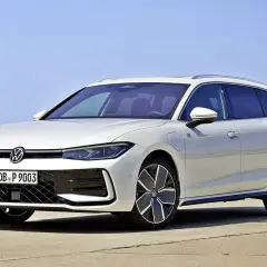 Biały Volkswagen Passat B9 Variant z nowoczesnymi felgami stoi na betonie, z błękitnym niebem w tle.