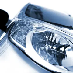 Zbliżenie na reflektor samochodu. Widać jeden reflektor, ale w rzeczywistości są dwa światła mijania.