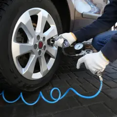 Rękawiczki chronią dłonie podczas sprawdzania ciśnienia w oponach. Manometr pokazuje aktualny stan powietrza.