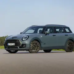 Szary Mini Clubman F54 z napędem ALL4 na tle lasu i łąki.
