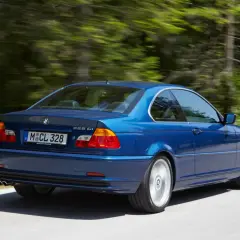 Niebieskie BMW E46 328 Ci z roku produkcji 2000, jadące po leśnej drodze.