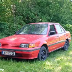 Czerwony Nissan Sunny N13, klasyk z lat 80., stoi na trawie, gotowy na nowe przygody.
