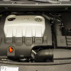 Silnik TDI z Volkswagena Touran 1T2. Widoczny jest srebrny dekiel z logo TDI i VW, przewody oraz zbiornik płynu chłodniczego.