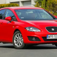Czerwony Seat Leon 1P1 z polskimi tablicami rejestracyjnymi WPR 10510 na drodze, z kierowcą za kierownicą.