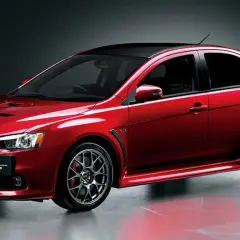 Czerwony Mitsubishi Lancer Evolution z czarnym dachem i spoilerem, gotowy do jazdy.