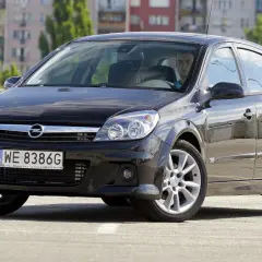 Czarny Opel Astra H na parkingu. Kierowca zastanawia się, jakie żarówki wybrać do swojego auta.