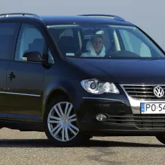 Czarny Volkswagen Touran 1T3 z młodym kierowcą za kierownicą, zaparkowany na drodze.