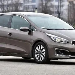 Brązowy Kia Ceed JD na tle budynków i drzew. Elegancki, miejski samochód gotowy na każdą podróż.