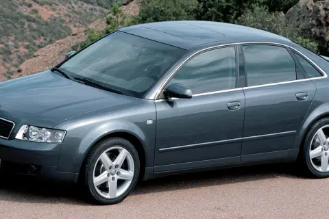 Szary sedan Audi A4 B6, produkowany w latach 2000-2006, parkuje na tle górskiego krajobrazu.