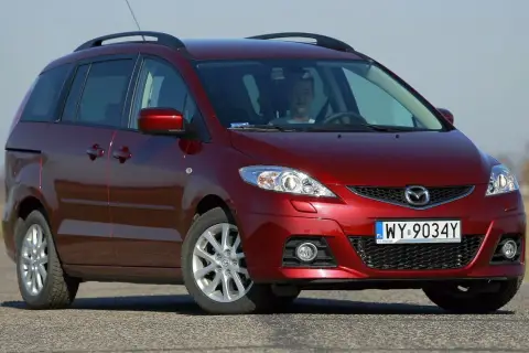 Czerwona Mazda 5 CR z młodym kierowcą za kierownicą, zaparkowana na drodze.