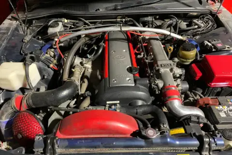 Silnik 2JZ-GE z turbosprężarką w Toyota Mark II. Widoczny czerwony filtr stożkowy i metalowe przewody dolotowe.