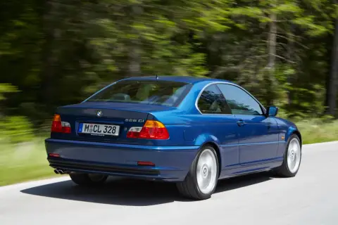 Niebieskie BMW E46 328 Ci z roku produkcji 2000, jadące po leśnej drodze.