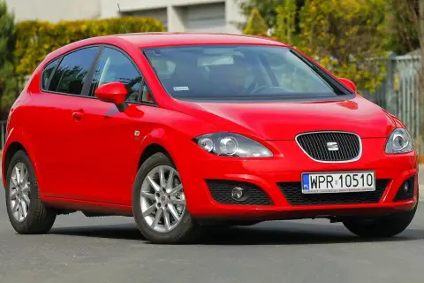 Czerwony Seat Leon 1P1 z polskimi tablicami rejestracyjnymi WPR 10510 na drodze, z kierowcą za kierownicą.
