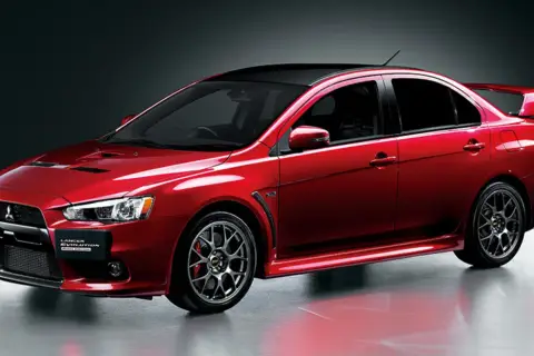 Czerwony Mitsubishi Lancer Evolution z czarnym dachem i spoilerem, gotowy do jazdy.