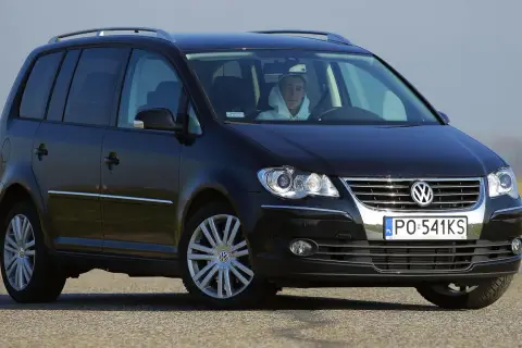 Czarny Volkswagen Touran 1T3 z młodym kierowcą za kierownicą, zaparkowany na drodze.