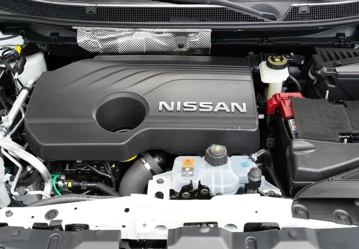 Silnik Nissana Qashqai J11, z widocznym napisem NISSAN na czarnej osłonie. Widać akumulator i zbiornik płynu chłodniczego.