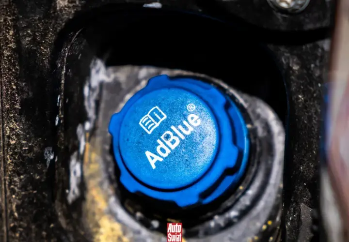Niebieski korek wlewu AdBlue w samochodzie, z widocznym logo i napisem.