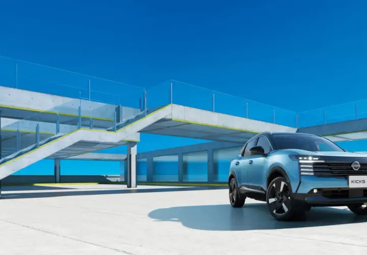 Niebieski Nissan Kicks stoi na betonowym placu przed nowoczesnym budynkiem z przeszklonymi oknami i betonowymi schodami.