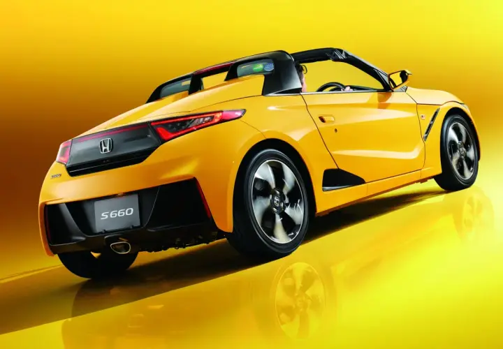 Żółta Honda S660 z otwartym dachem, widziana z tyłu, błyszczy na tle.