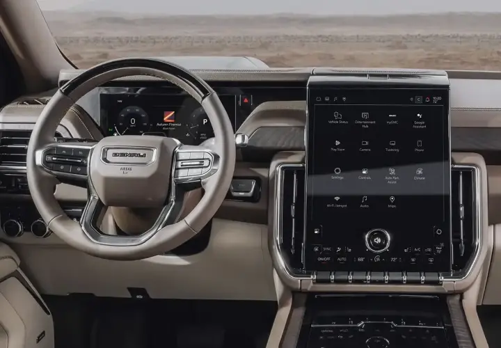 Wnętrze GMC Yukon XL z dużym ekranem dotykowym, kierownicą Denali i cyfrowymi wskaźnikami.
