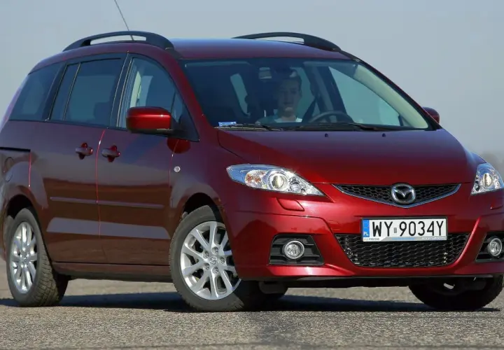 Czerwona Mazda 5 CR z młodym kierowcą za kierownicą, zaparkowana na drodze.