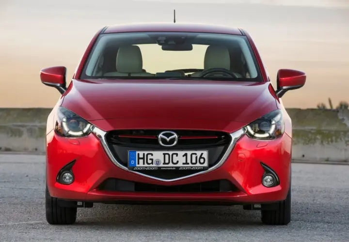 Czerwona Mazda 2 DY z przodu, z widocznymi światłami LED i tablicą rejestracyjną.