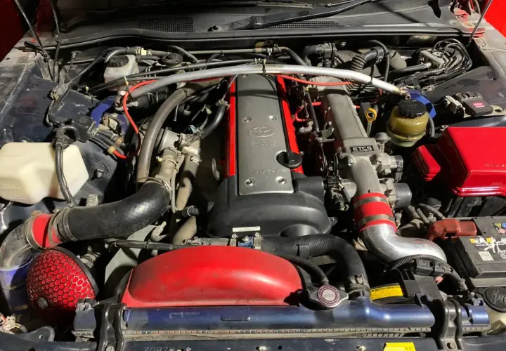 Silnik 2JZ-GE z turbosprężarką w Toyota Mark II. Widoczny czerwony filtr stożkowy i metalowe przewody dolotowe.