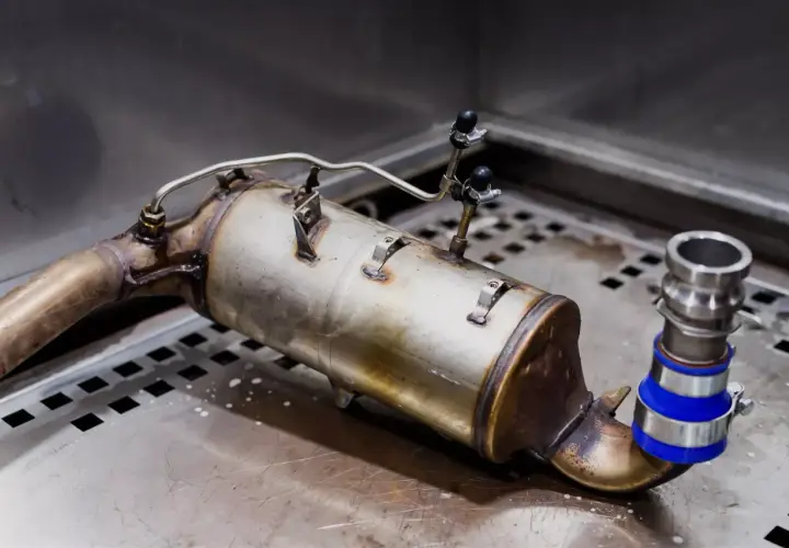 Element układu wydechowego, prawdopodobnie filtr DPF lub katalizator, z widocznymi przyłączami. Może to być związane z objawami awarii zaworu EGR.