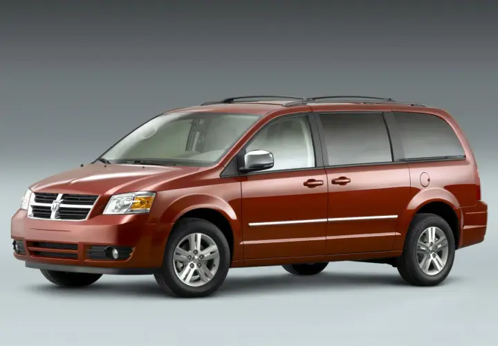 Pomarańczowy Dodge Grand Caravan z chromowanymi listwami i relingami dachowymi, gotowy na rodzinną podróż.