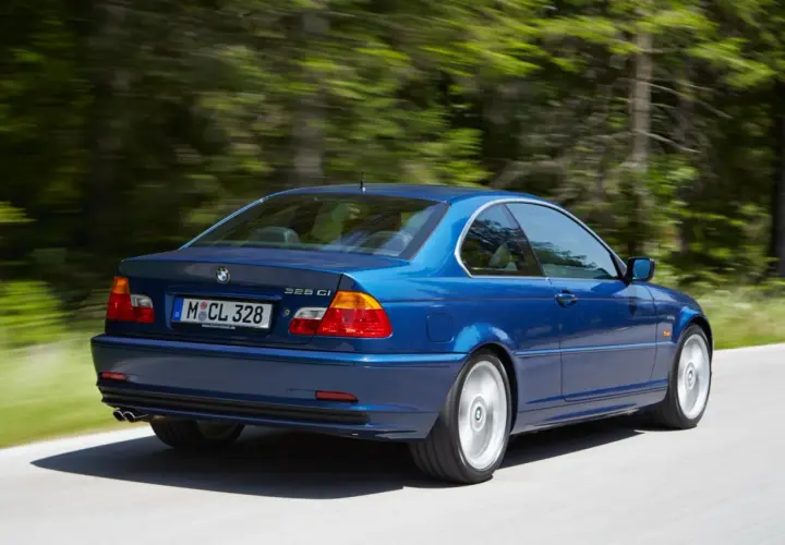 Niebieskie BMW E46 328 Ci z roku produkcji 2000, jadące po leśnej drodze.