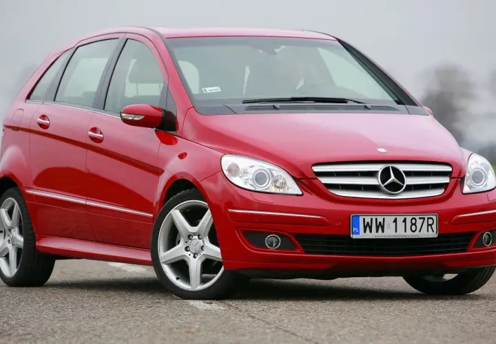 Czerwony Mercedes W245 na drodze, z widocznym grillem i reflektorami.
