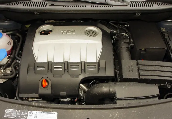 Silnik TDI z Volkswagena Touran 1T2. Widoczny jest srebrny dekiel z logo TDI i VW, przewody oraz zbiornik płynu chłodniczego.