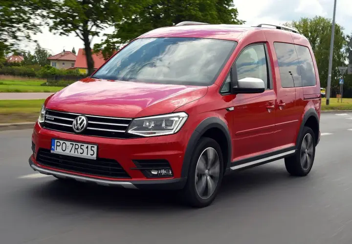 Czerwony Volkswagen Caddy 3 w ruchu, z widocznymi felgami i terenowym wyglądem.