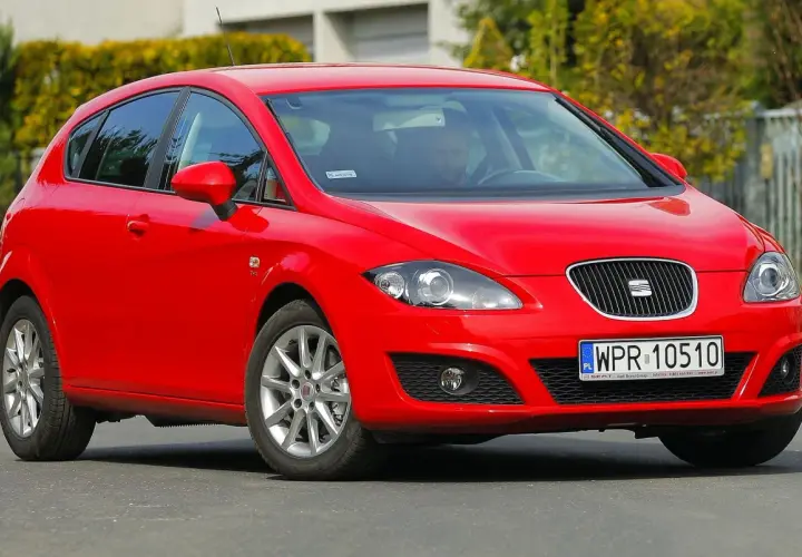 Czerwony Seat Leon 1P1 z polskimi tablicami rejestracyjnymi WPR 10510 na drodze, z kierowcą za kierownicą.
