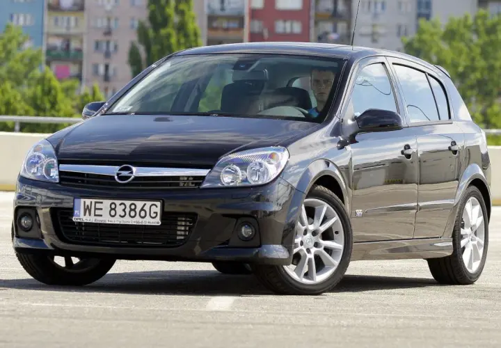 Czarny Opel Astra H na parkingu. Kierowca zastanawia się, jakie żarówki wybrać do swojego auta.