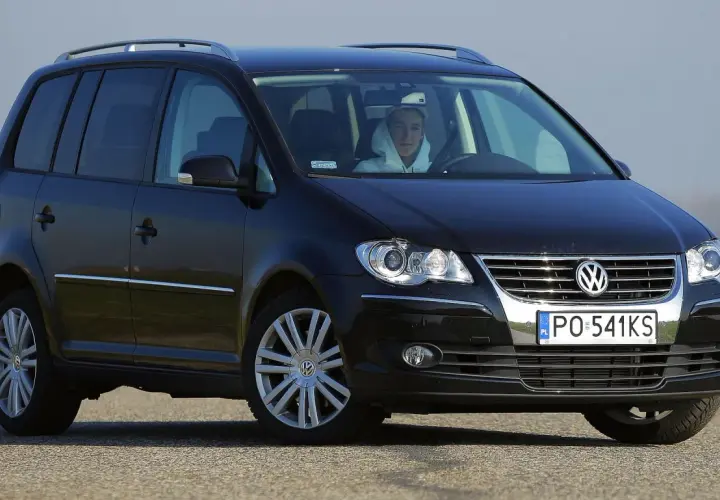 Czarny Volkswagen Touran 1T3 z młodym kierowcą za kierownicą, zaparkowany na drodze.