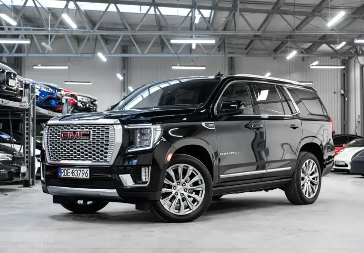 Czarny GMC Yukon Denali lśni w salonie samochodowym, gotowy na przygodę.